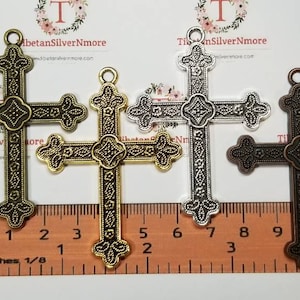 May include: Three ornate metal cross charms in gold, silver, and bronze finishes. Each cross measures approximately 2 inches in length. The crosses have a detailed design with intricate patterns and a slightly raised center.