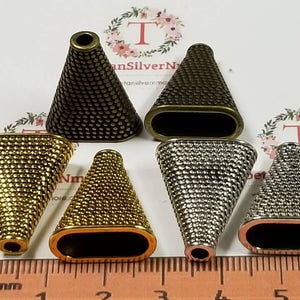 May include: Six metal cone-shaped end caps in various finishes, including gold, silver, and bronze. The caps have a textured surface and are approximately 1 inch in length.