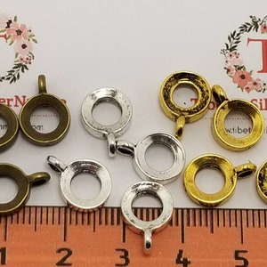 Puede incluir: Surtido de 10 engastes de bisel de metal para la elaboración de joyas. Los engastes son de tres colores: latón antiguo, plata y oro. Cada engaste tiene una abertura redonda y un bucle para sujetarlo a una cadena o cordón. Los engastes tienen un diámetro aproximado de 2,5 cm.