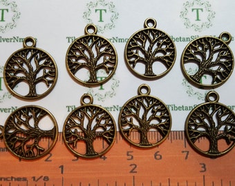 May include: Eight antique gold-toned metal tree of life charms. The charms are round and feature a detailed tree design with branches and leaves. The charms are approximately 1 inch in diameter and have a loop at the top for hanging.