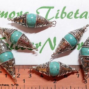 May include: Five turquoise and silver pendant charms with ornate designs. The charms are approximately 1.5 inches long and have a loop at the top for attaching to a necklace or bracelet.