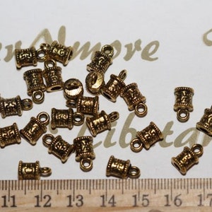 May include: A collection of gold-toned metal end caps for cords or jewelry. The end caps have a decorative design and a small loop at the top.
