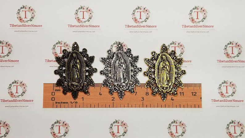 Puede incluir: Tres encantos de metal con una figura religiosa en un marco decorativo. Los encantos son de color dorado, plateado y bronce. Los encantos miden aproximadamente 5 cm de largo.