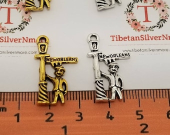 May include: Two silver charm pendants featuring a street sign that reads "NEW ORLEANS". The charms are approximately 2.5 cm in height and are displayed on a ruler for scale.