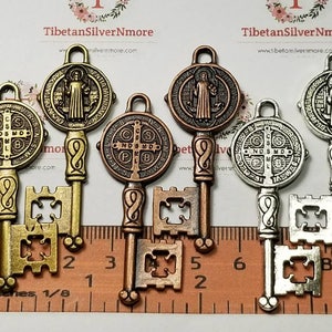 Puede incluir: Cuatro encantos de llave de estilo antiguo con un diseño de medalla de San Benito. Las llaves son de metal y tienen un acabado dorado, cobre y plateado. Las medallas presentan una cruz y la inscripción "S.P.D.B.  Las llaves miden aproximadamente 5 cm de largo.