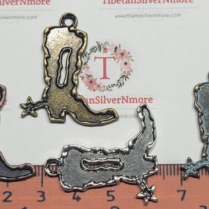 May include: Four antique silver cowboy boot charms with a spur detail. The charms are approximately 2 inches in length and have a loop at the top for hanging.
