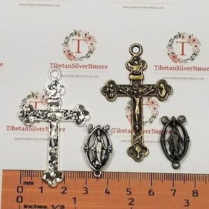 May include: Two silver and one gold-toned metal religious charms. The silver charms are crucifixes with a figure of Jesus Christ on the cross. The gold-toned charm is a depiction of the Virgin Mary. The charms are approximately 1.5 inches in length.