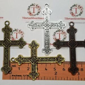 May include: Three ornate metal cross charms in silver, gold, and bronze finishes. Each cross measures approximately 2 inches in length and features intricate details.
