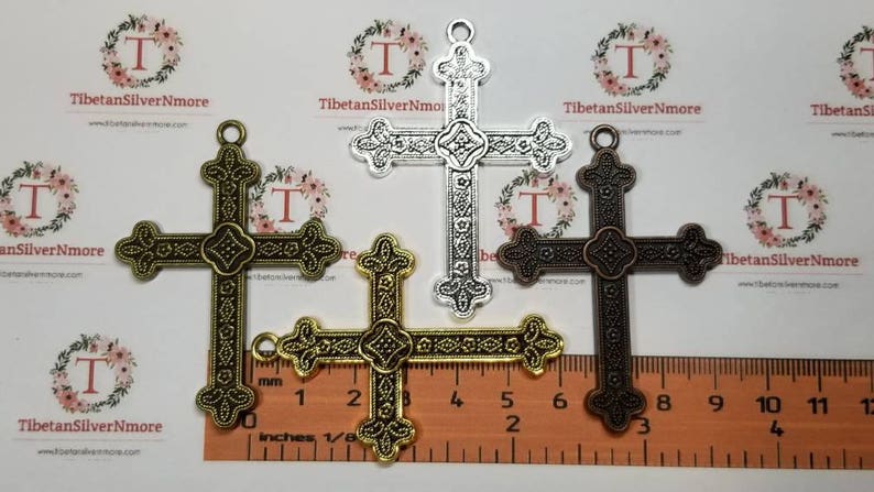 May include: Three ornate metal cross charms in silver, gold, and bronze finishes. Each cross measures approximately 2 inches in length and features intricate details.