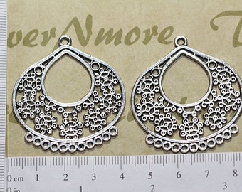 May include: Two silver filigree earring blanks with a teardrop shape and a circular opening in the center. The blanks are approximately 2 inches in length.