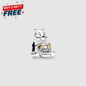 May include: A silver charm featuring a smiling bear holding a honey pot. The honey pot has the word "HUNN" on it. The image also includes the text "BUY 2 GET 1 FREE" in red, white, and blue.