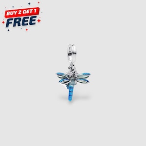 May include: A silver dragonfly charm with blue enamel wings and a blue body. The charm has a small loop at the top for attaching to a bracelet or necklace. The dragonfly has a detailed design with small crystals.