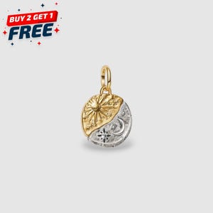 Pode incluir: Um pingente de ouro e prata com um design de sol e lua. O pingente é dividido em duas metades, com um sol dourado de um lado e uma lua prateada, estrelas e um pequeno diamante do outro. O texto "BUY 2 GET 1 FREE" está no canto superior esquerdo.