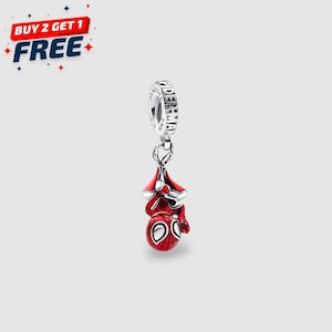 May include: A silver charm featuring a red and black Spider-Man design. The charm is hanging upside down, with a detailed depiction of the character's mask and suit. The charm has a silver ring with the word "SPIDERMAN" engraved on it.