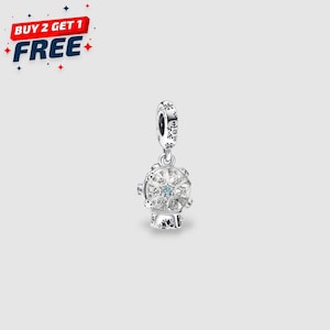 May include: A silver charm with a snow globe design. The charm features a clear globe filled with sparkling crystals and a central blue gem. The top of the charm has a decorative design, and the text "BUY 2 GET 1 FREE" is in the upper left corner.