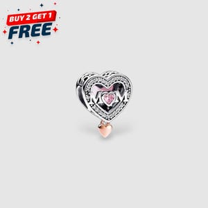 May include: A silver heart-shaped charm with the word "MOM" in the center, accented with a pink heart and clear crystals. A smaller rose gold heart dangles below. The image also includes the text "BUY 2 GET 1 FREE".