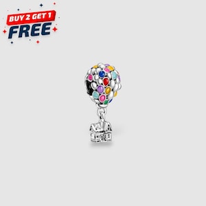 May include: A silver charm featuring a colorful hot air balloon design with a house pendant. The balloon is composed of various colored enamel dots. The charm has the text "BUY 2 GET 1 FREE" in the upper left corner.