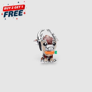 Könnte beinhalten: Ein silberner Charm in Form eines Cartoon-Rentiers, das eine Karotte hält. Das Rentier hat braune und weiße Flecken, große Augen und silberne Geweihe. Der Charm hat den Text "BUY 2 GET 1 FREE" in einem rot-blauen Banner.