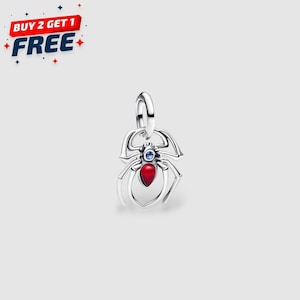 May include: A silver spider charm with a red teardrop-shaped gem on its abdomen and a blue gem on its head. The charm has a loop for attaching to a bracelet or necklace. The image also includes the text "BUY 2 GET 1 FREE".