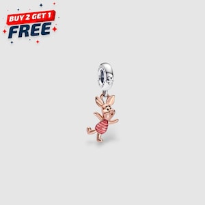 Puede incluir: Un charm de oro rosa con un cerdo de dibujos animados con una camisa a rayas rojas y blancas. El charm cuelga de un anillo plateado con un diseño floral. La imagen también incluye el texto "BUY 2 GET 1 FREE".
