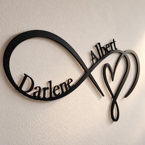 May include: A black wall-mounted sign featuring an infinity symbol intertwined with a heart shape. The name Darlene is integrated into the left loop of the infinity symbol, while the name Albert is integrated into the right side of the design.