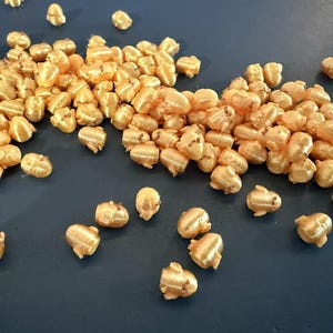 Könnte beinhalten: Set aus drei Keramikbechern mit gesprenkelter, matter Oberfläche. Die Becher sind in Creme-, Hellgrau- und Dunkelgrautönen gehalten. Jeder Becher hat ein schlichtes, minimalistisches Design.
