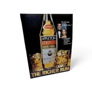Pode incluir: Um anúncio retangular de Appleton Gold Jamaica Rum com uma garrafa de rum âmbar, dois copos cheios de gelo e um casal. O texto diz: We drink rum because we like the taste, and frankly, we believe it's tasteless to drink any other rum. THE RICHER RUM.
