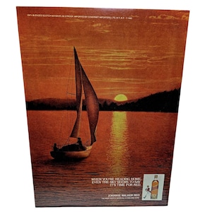 May include: An advertisement for Johnnie Walker Red featuring a sailboat on a lake at sunset. The sky and water are shades of orange and red. Text reads "When you're heading home, even the sky seems to say it's time for Red."