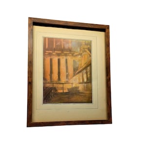 Puede incluir: Impresión enmarcada de época que representa una escena industrial con estructuras imponentes y un puente. La obra de arte presenta tonos cálidos de naranja, marrón y amarillo, enmarcada en un marco de madera marrón oscuro. La impresión está montada sobre un passe-partout crema.