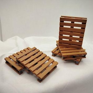 Könnte beinhalten: Mehrere kleine Holzpaletten in warmbrauner Farbe sind auf einer weißen Oberfläche angeordnet. Die Paletten haben ein Latten-Design und sind in verschiedenen Konfigurationen gestapelt. Diese kleinen Paletten dienen wahrscheinlich dekorativen Zwecken.