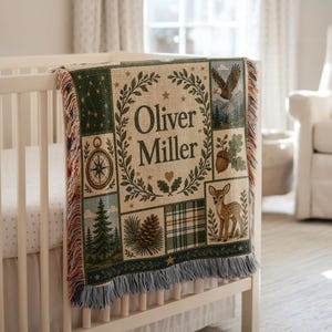 May include: A woven throw blanket featuring the name Oliver Miller in the center, surrounded by illustrations of a compass, a bald eagle, an acorn, a pine tree, a pinecone, a deer, and a plaid pattern, finished with fringed edges.