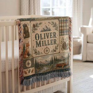 Peut inclure: Un plaid tissé présentant un collage sur le thème de la nature avec le texte Oliver Miller. Le motif comprend un renard, un sac à dos, un canoë sur un lac, des montagnes, des pins et une boussole. Le plaid a un bord frangé et une bordure multicolore.