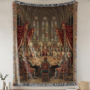 Può includere: Coperta arazzo tessuta raffigurante una scena medievale di un re e cavalieri a un tavolo rotondo. L'opera d'arte raffigura una grande sala con vetrate, drappeggi rossi e candele accese. La coperta ha un bordo con frange.