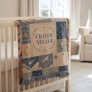 May include: A woven throw blanket featuring a celestial theme with a central rectangular panel displaying the name Oliver Miller surrounded by a laurel wreath. The design includes illustrations of a telescope, planets, stars, and clouds.