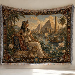 Könnte beinhalten: Ein gewebter Wandteppich mit einer ägyptischen Szene, die eine Figur in traditioneller Kleidung neben einem Leoparden zeigt. Der Hintergrund zeigt Pyramiden, einen Obelisken, Palmen und Boote auf einem Fluss. Der Rand ist mit Blumenmotiven verziert.