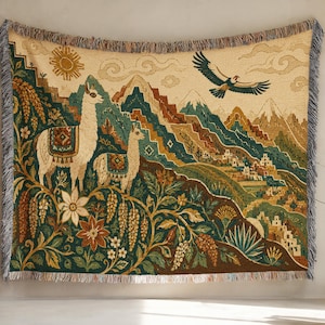 Op de afbeelding: Een geweven wandtapijtdeken met twee lama's op de voorgrond, een vliegende adelaar en een berglandschap met een dorp. Het ontwerp bevat florale elementen, een zon en wolken in tinten groen, bruin, crème en blauw met franjes aan de randen.