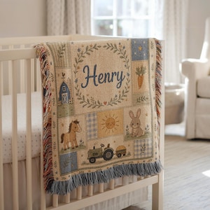 May include: A woven throw blanket featuring a farm theme with the name Henry in blue script. The design includes a barn, a horse, a tractor, a rabbit, a sun, and carrots in a grid pattern with fringe edges on the top and bottom sides.