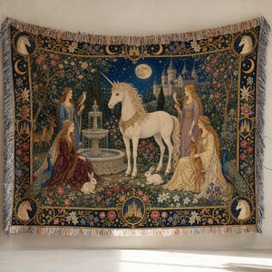 Può includere: Una coperta in arazzo intrecciato con un unicorno bianco centrale vicino a una fontana in pietra in un giardino. Tre figure in abiti in stile medievale sono circondate da conigli, cervi, pavoni e un castello sotto la luna piena, con frange.
