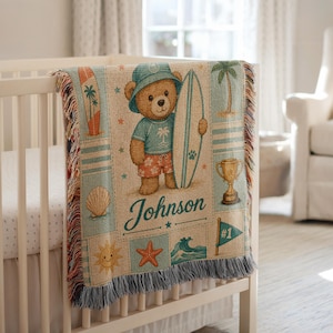 May include: A woven throw blanket featuring a central illustration of a teddy bear wearing a blue bucket hat and floral shorts while holding a surfboard. The design includes palm trees, a seashell, a trophy, a starfish, and the name Johnson.