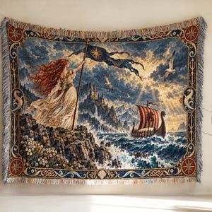 May include: A woven tapestry blanket featuring a red-haired figure in a white dress holding a blue flag on a rocky cliff. The scene includes a Viking ship on a turbulent sea, mountains, seagulls, and a decorative border with nautical motifs.
