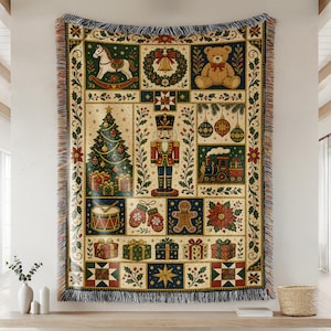 May include: A woven throw blanket featuring a grid of Christmas-themed illustrations including a nutcracker, teddy bear, rocking horse, decorated tree, train, gingerbread man, mittens, drum, poinsettias, and wrapped gifts with fringed edges.