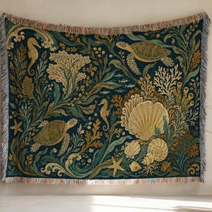 May include: A rectangular woven throw blanket featuring a dark teal background with a detailed marine life pattern. The design includes sea turtles, seahorses, starfish, various seashells, and coral reef vegetation in shades of gold, green, and tan.
