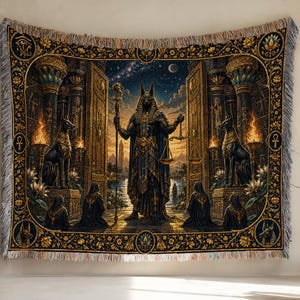 May include: A woven tapestry featuring a central figure of the Egyptian deity Anubis holding a staff and scales. The scene is framed by ornate columns, flaming torches, and kneeling figures, all rendered in deep blues, golds, and blacks with fringe.