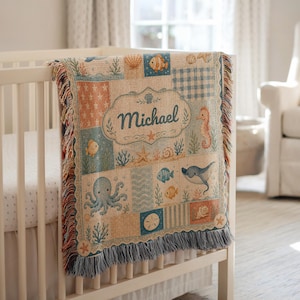 May include: A woven throw blanket featuring a patchwork design with various sea creatures including an octopus, seahorse, stingray, and fish. The center displays the name Michael in a decorative frame, surrounded by seashells and coral motifs.