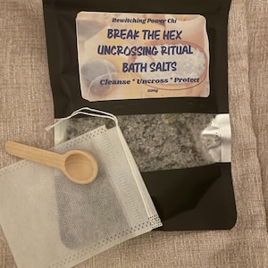 May include: A black resealable pouch containing grey bath salts with a label reading "Bewitching Power Chi BREAK THE HEX UNCROSSING RITUAL BATH SALTS Cleanse * Uncross * Protect 200g". A small white fabric sachet and a wooden scoop are included.