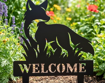 Könnte beinhalten: Schwarzer Metall-Gartenstecker mit einer Fuchssilhouette im Gras und dem ausgeschnittenen Wort "WELCOME". Der Fuchs blickt nach rechts, mit detaillierten Konturen. Der Hintergrund zeigt einen Garten mit bunten Blumen.