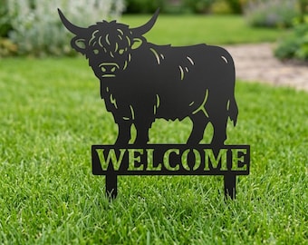 Könnte beinhalten: Ein schwarzer Gartenstecker aus Metall mit der Silhouette eines Hochlandrindes mit langen Hörnern und zotteligem Fell. Unter dem Rind befindet sich ein rechteckiges Schild mit dem ausgeschnittenen Wort WELCOME in Großbuchstaben auf zwei Stäben.