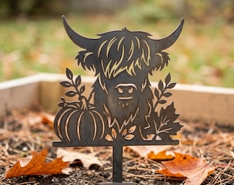Könnte beinhalten: Ein Gartenstecker aus dunklem Metall mit einer ausgeschnittenen Silhouette eines Hochlandrind-Kopfes mit langen Hörnern, neben einem Kürbis und einem Ahornblatt. Das Motiv ist auf einem vertikalen Stab mit einer flachen Basis montiert.