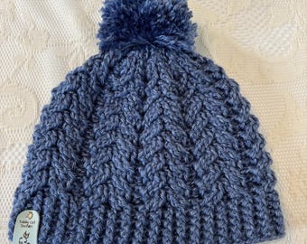 Cappello lavorato a maglia blu con pompon