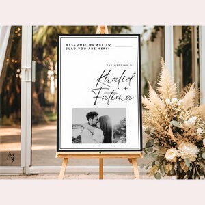 A wedding welcome sign for Khalid and Fatima on a wooden easel placed next to a large arrangement of dried pampas grass and white flowers.